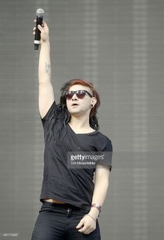 a woman in black shirt and sunglasses holding up a cell phone to the sky with one hand