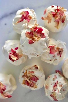 several desserts with white frosting and red flowers on them