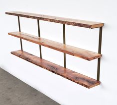 three wooden shelves on the wall with metal bars attached to each shelf and one is empty