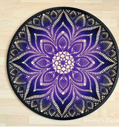 a blue and white doily with an intricate design in the center on a wooden floor