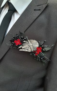 a man in a suit and tie with a red flower brooch on his lapel