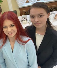 two young women standing next to each other in front of a table