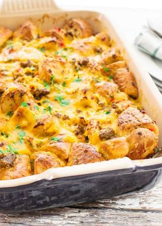 a casserole dish with meat and cheese in it sitting on a table next to utensils