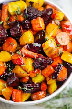 roasted beets and carrots with herbs in a white bowl on a wooden table