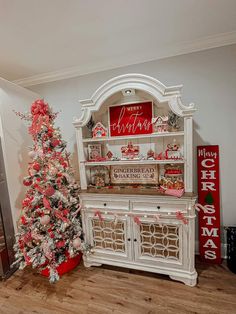 a decorated christmas tree in front of a white hutch with red and silver decorations