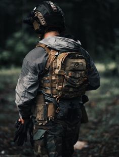 a man in camouflage is walking through the woods with his back turned to the camera