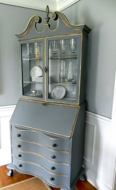 an antique china cabinet with glass doors and drawers in the corner of a living room