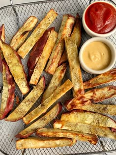 baked french fries with ketchup and mustard on a cooling rack next to dipping sauce