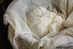 an unmade bed with white sheets on top of it and a person in the background