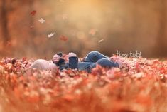 two people are laying in the grass with leaves flying around them and one person is holding his head