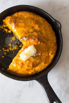 a skillet with some food in it on a counter top next to a spoon