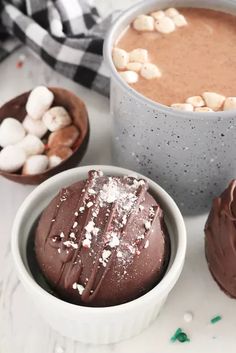 two cups filled with hot chocolate and marshmallows on top of a table