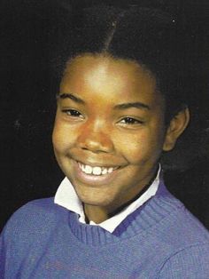 a young boy wearing a blue sweater and white collared shirt smiling at the camera