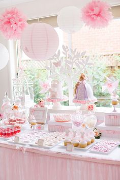 a table topped with lots of pink and white desserts