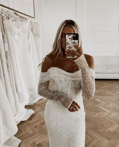 a woman taking a selfie in a white dress with long sleeves and sequins