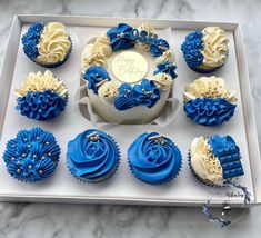 blue and white cupcakes are arranged in a box