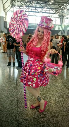 a woman dressed in pink holding a candy cane and wearing a dress with polka dots