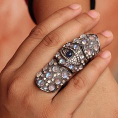 a close up of a person wearing a ring with diamonds and blue stones on it