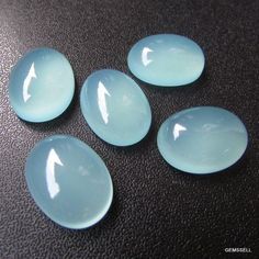 four blue glass plates sitting on top of a black table next to an orange cell phone