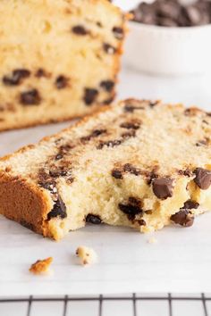 a loaf of chocolate chip bread on a cooling rack next to a bowl of chocolate chips