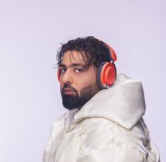 a man with headphones on his ears wearing a white jacket and orange hoodie