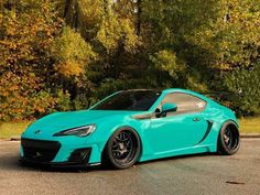 a blue sports car parked in front of some trees