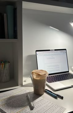 an open laptop computer sitting on top of a desk next to a cup of coffee