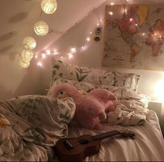 a pink teddy bear laying on top of a bed next to a string of lights