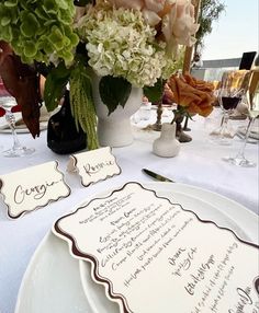 the table is set with flowers and place cards for guests to write their names on