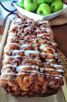 a loaf of cinnamon apple bread sitting on top of a table next to green apples