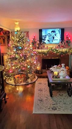 a living room with a christmas tree in the corner and a television on above it