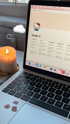 an open laptop computer sitting on top of a desk next to a cup and candle