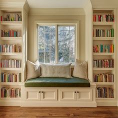 a window seat with bookshelves and pillows in front of a window filled with books