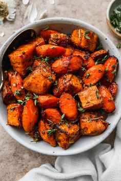 a white bowl filled with cooked carrots and herbs