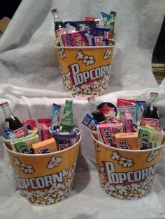 three buckets filled with different types of snacks and drinks on a white table cloth