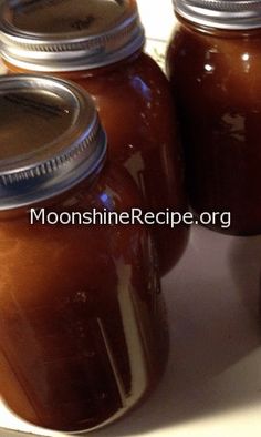 three jars filled with brown liquid sitting on top of a counter