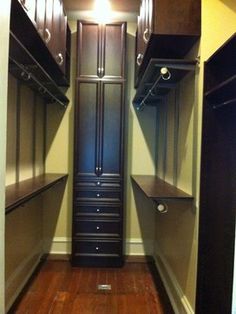 an empty walk - in closet with wooden floors and black cabinetry on the walls