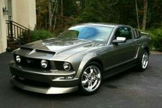 a silver mustang parked in front of a house