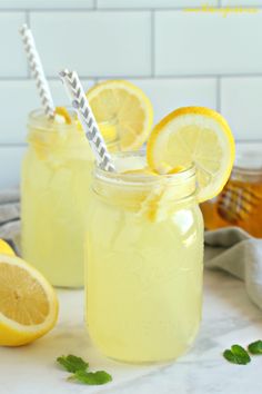 two glasses filled with lemonade and garnished with limes on a white tray