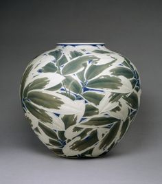 a white and green vase with leaves on it