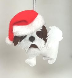 a dog ornament with a santa hat hanging from it's side on a chain