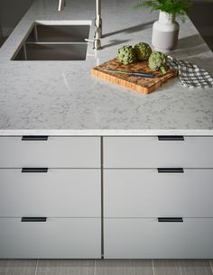 a cutting board with some green vegetables on it next to a sink and counter top