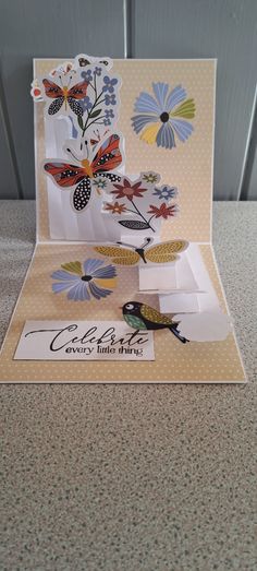 an open card with flowers and butterflies on it, sitting on top of a table