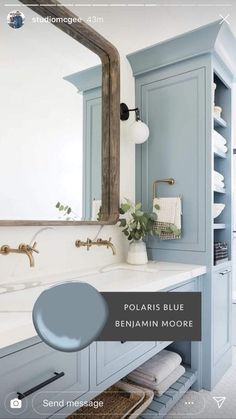 a bathroom with blue cabinets and white counter tops, along with a large mirror above the sink