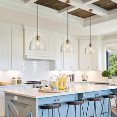 a kitchen island with stools and lights hanging from it's ceiling over the counter