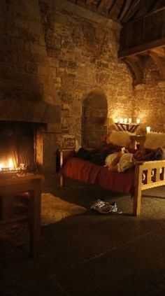 a room with a bed, fireplace and candles on the wall in it's center