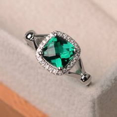 a ring with a green stone surrounded by diamonds