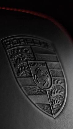 a close up of the emblem on a black leather car seat with red stitching