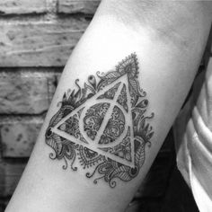 a black and white photo of a harry potter tattoo on the left arm, with an intricate