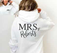 a woman wearing a white hoodie with the words mrs roberts on it and black lettering